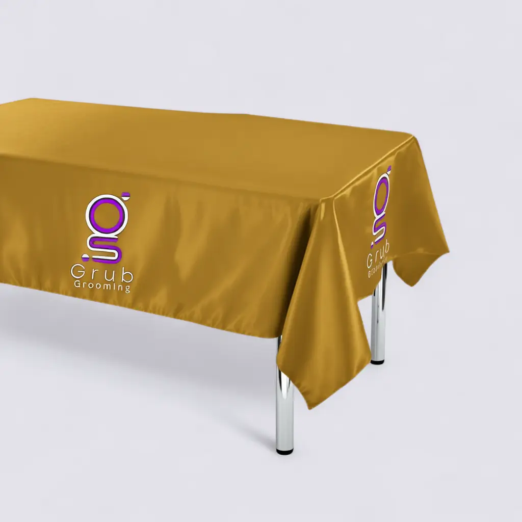 Mantel de presentación dorado de GRUB Grooming. Accesorio de alta calidad con bordado central del logo, diseñado para aportar elegancia y profesionalismo en mesas de grooming o exhibiciones. Material satín brillante, bordes reforzados y medidas 1.40 m x 0.70 m.